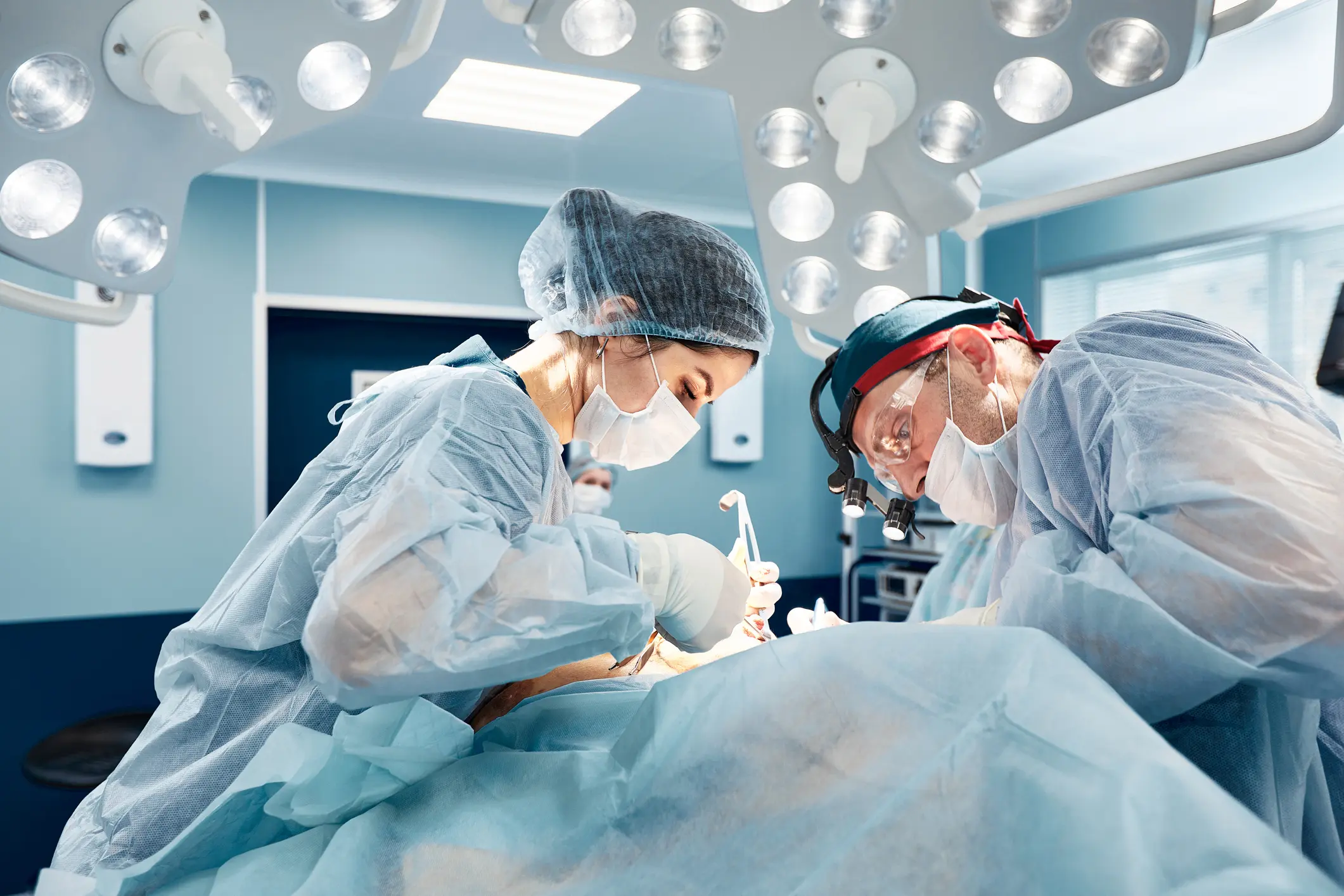 Doctors in surgical attire in operating room.
